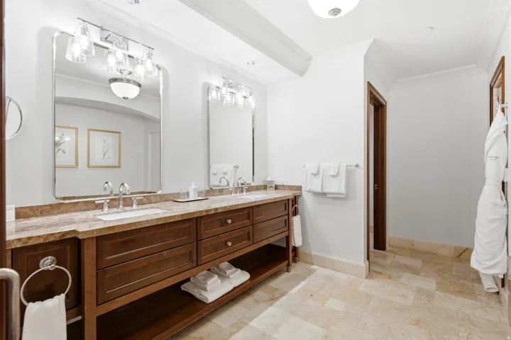 Dual vanity with a stone countertop, individual mirrors, and multi-bulb light fixtures