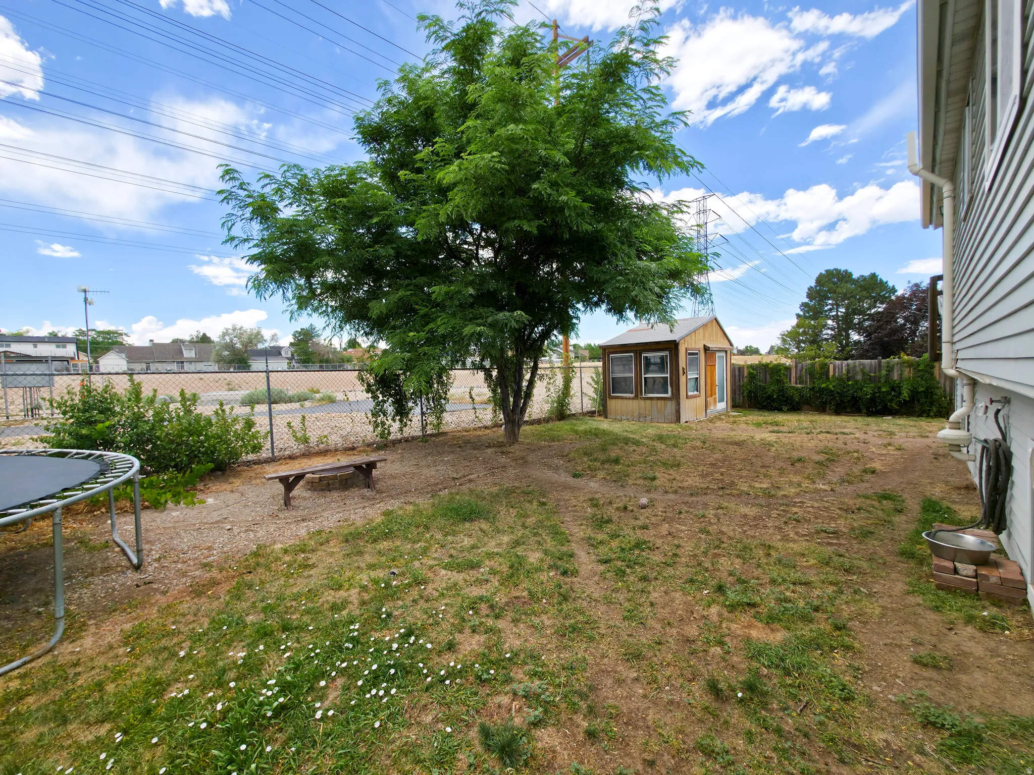 Back yard: open behind, firepit at center, shed on right.