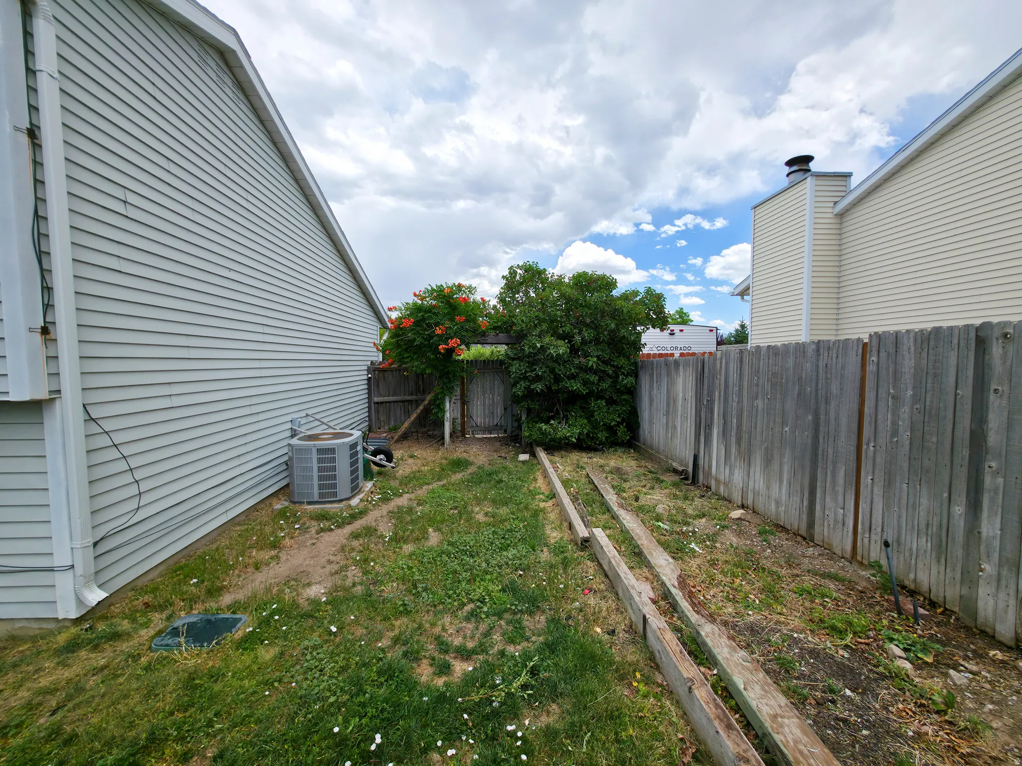 Back yard, south side, AC on left, vegetable garden on right.