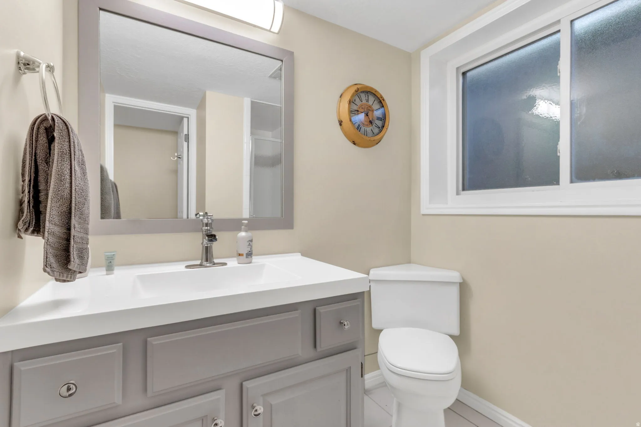 basement Bathroom. Vanity with a white countertop and integrated sink, chrome faucet, and gray cabinetry