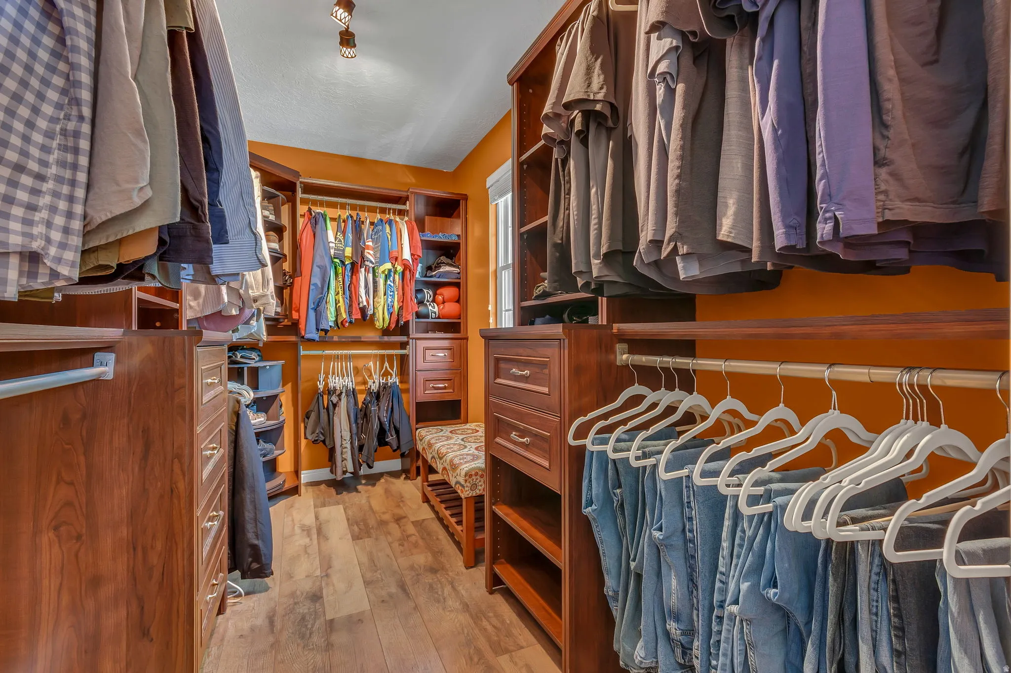 Master custom closet system featuring built-in cabinetry and wood-finish flooring