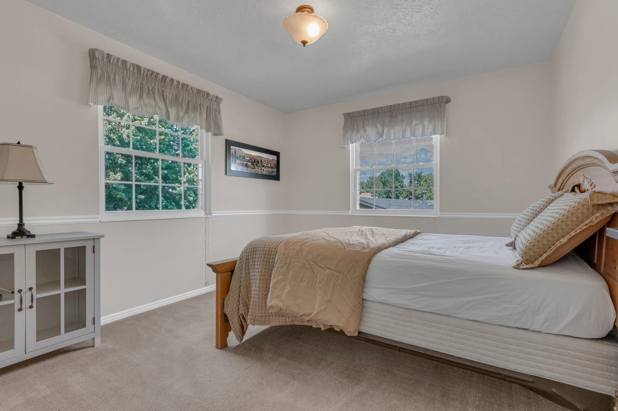 Bedroom 2:  featuring two multi-pane windows, neutral-toned walls, chair rail molding, and a carpeted floor