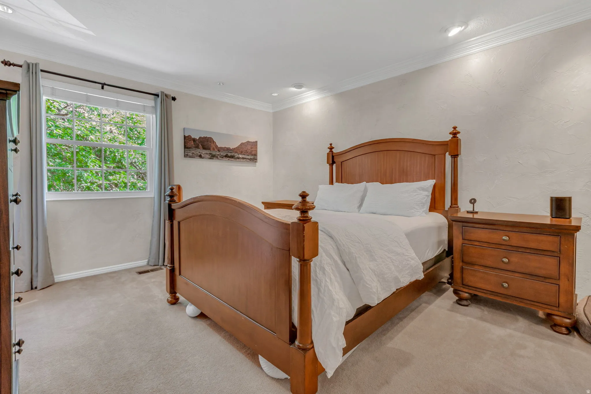 Master bedroom featuring a large window with green scenery, recessed lighting, crown molding, and textured walls