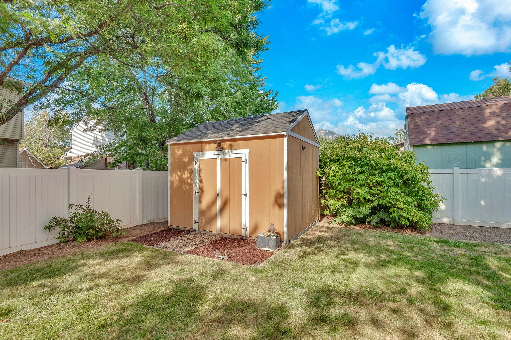 Backyard storage shed with double doors, pitched roof, and exterior lighting. She dis included.