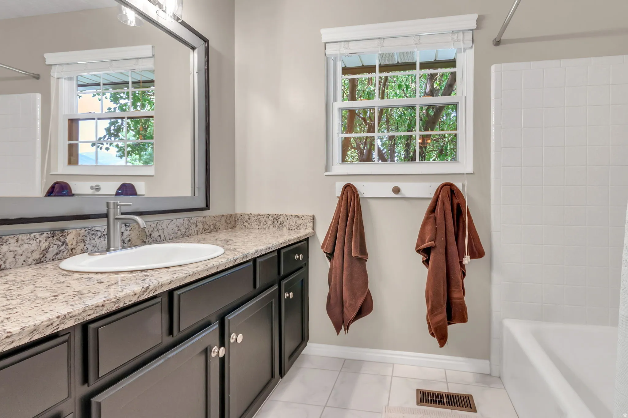 Upstairs Bathroom 3: featuring a vanity with dark cabinetry, a light speckled countertop, an undermount sink, and a modern single-handle faucet