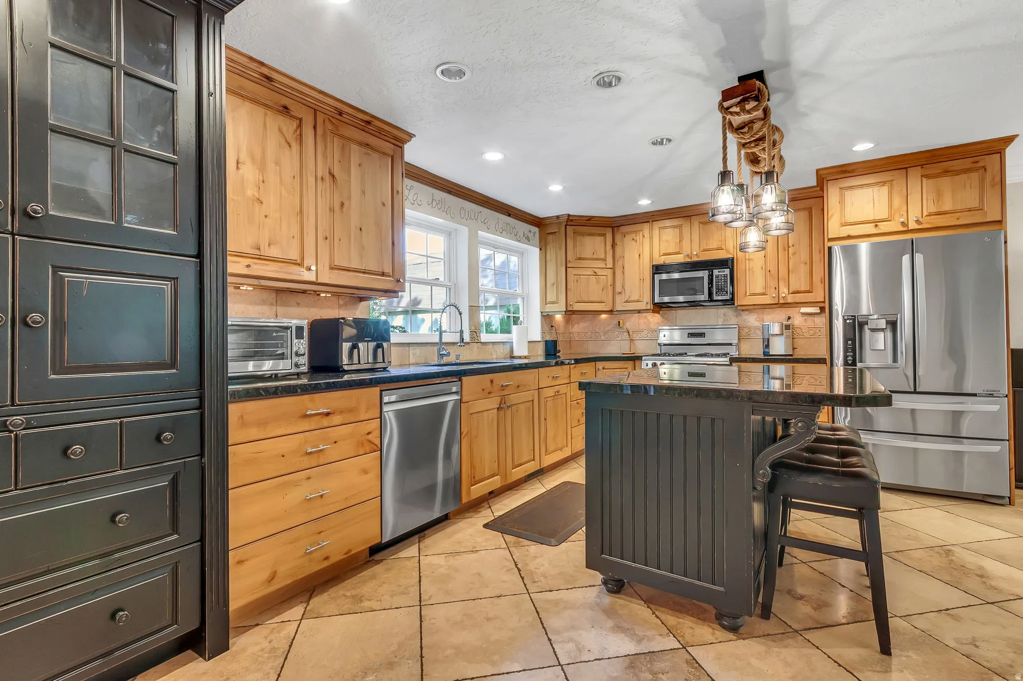 Kitchen featuring wood-finish cabinetry, black countertops, and stainless steel appliances