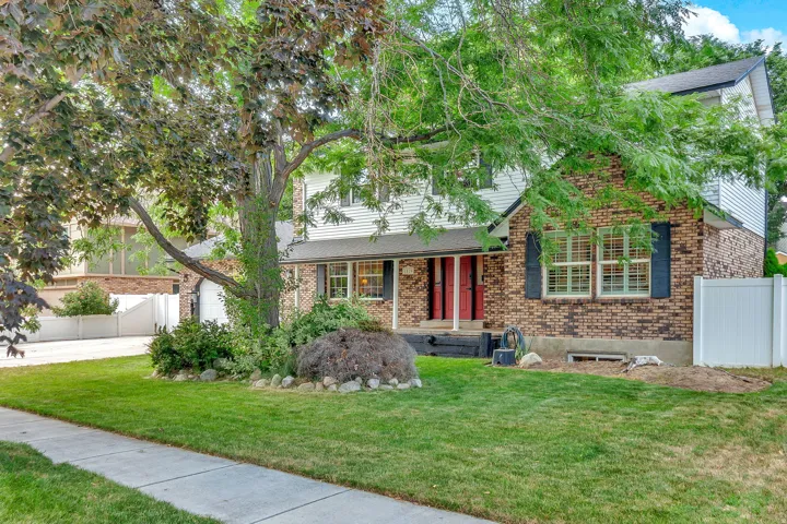 Traditional two-story residence featuring a brick and siding exterior, red entry doors, and a well-maintained front lawn