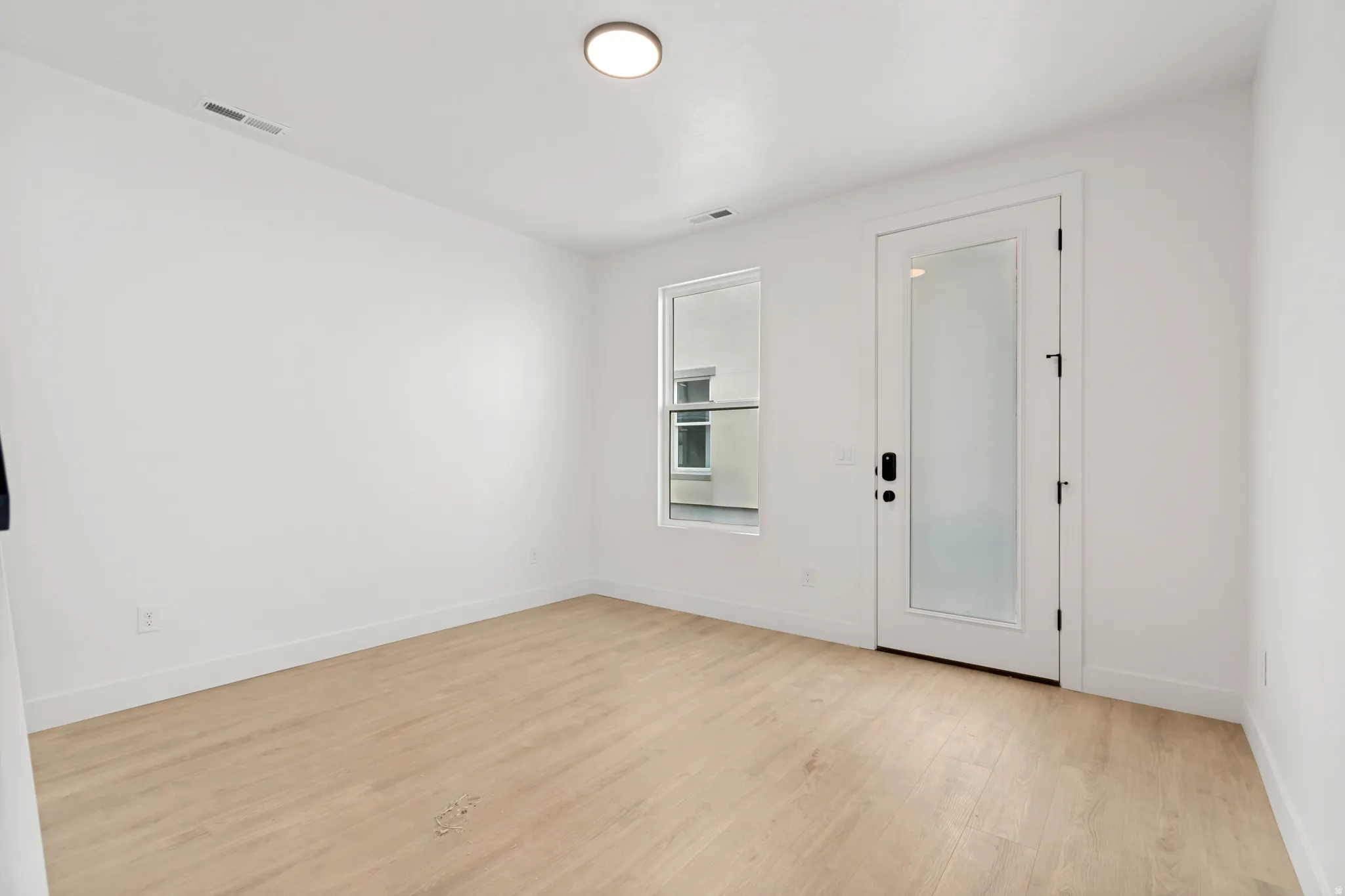 Light wood-finish flooring, white walls, and a recessed ceiling light