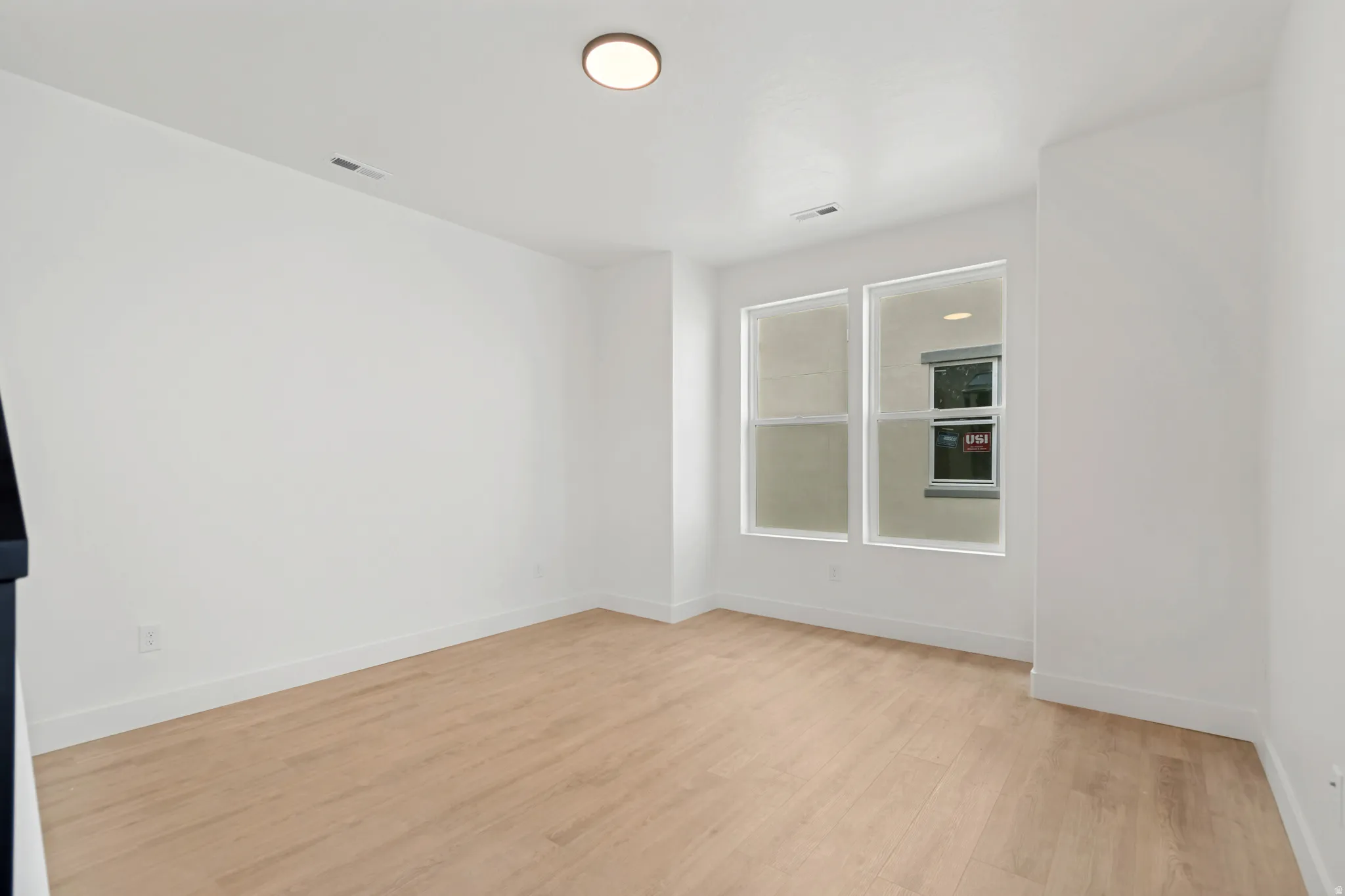Recessed lighting, light wood-finish flooring, white walls, two vertical windows