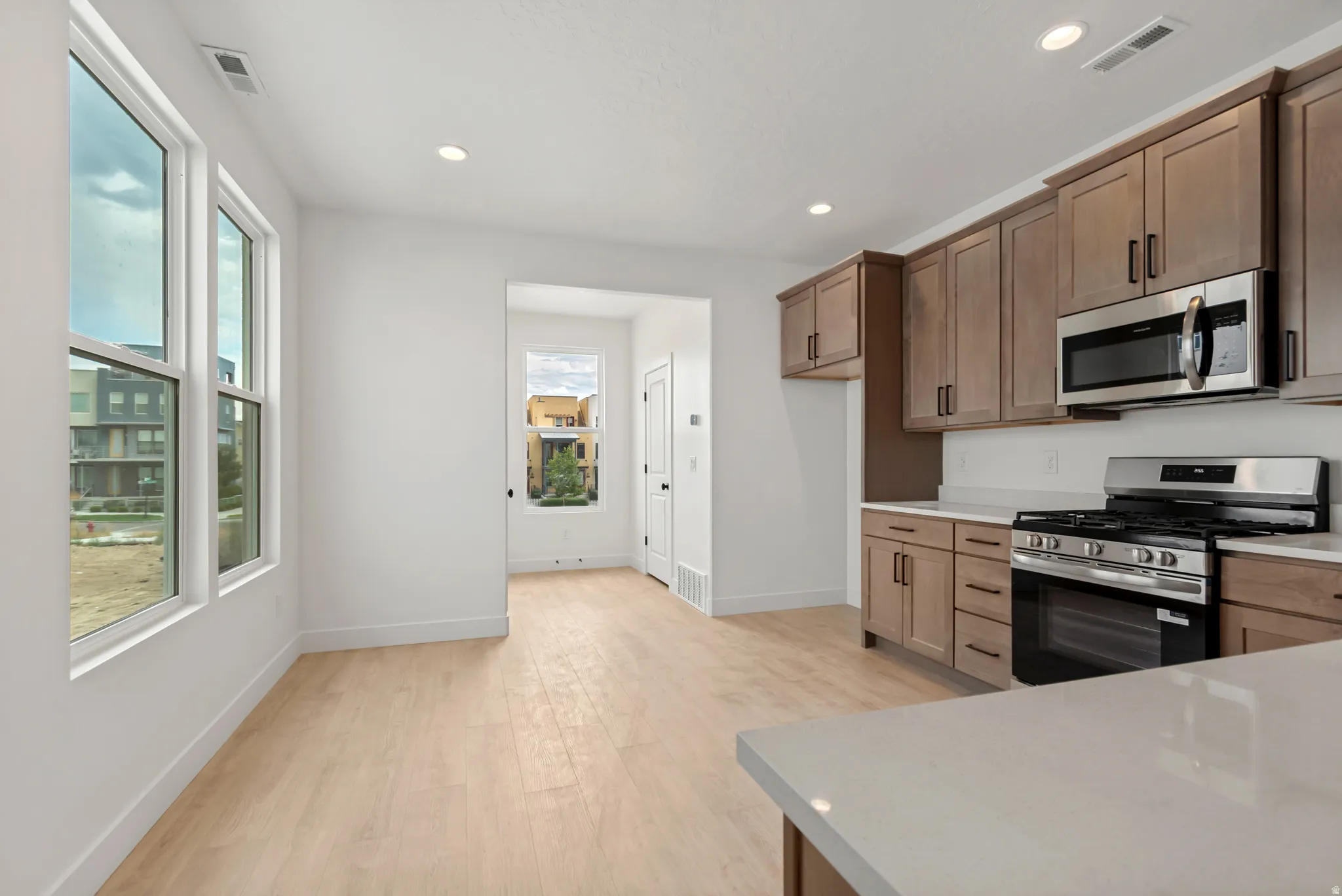 Open-concept kitchen with wood-finish flooring, recessed lighting, and white walls
