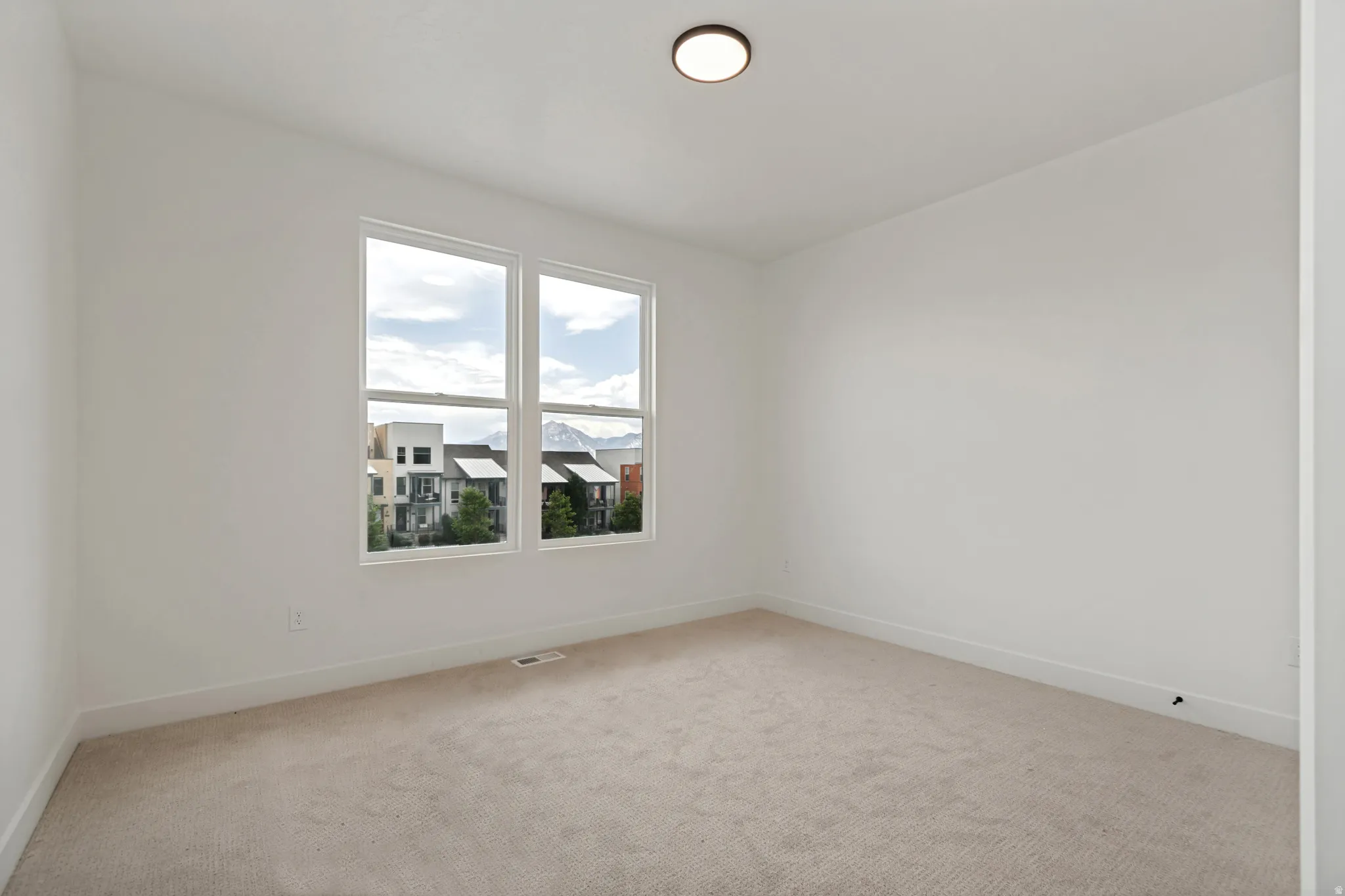 Neutral wall finishes, light-toned carpeting, and a flush-mount ceiling light fixture