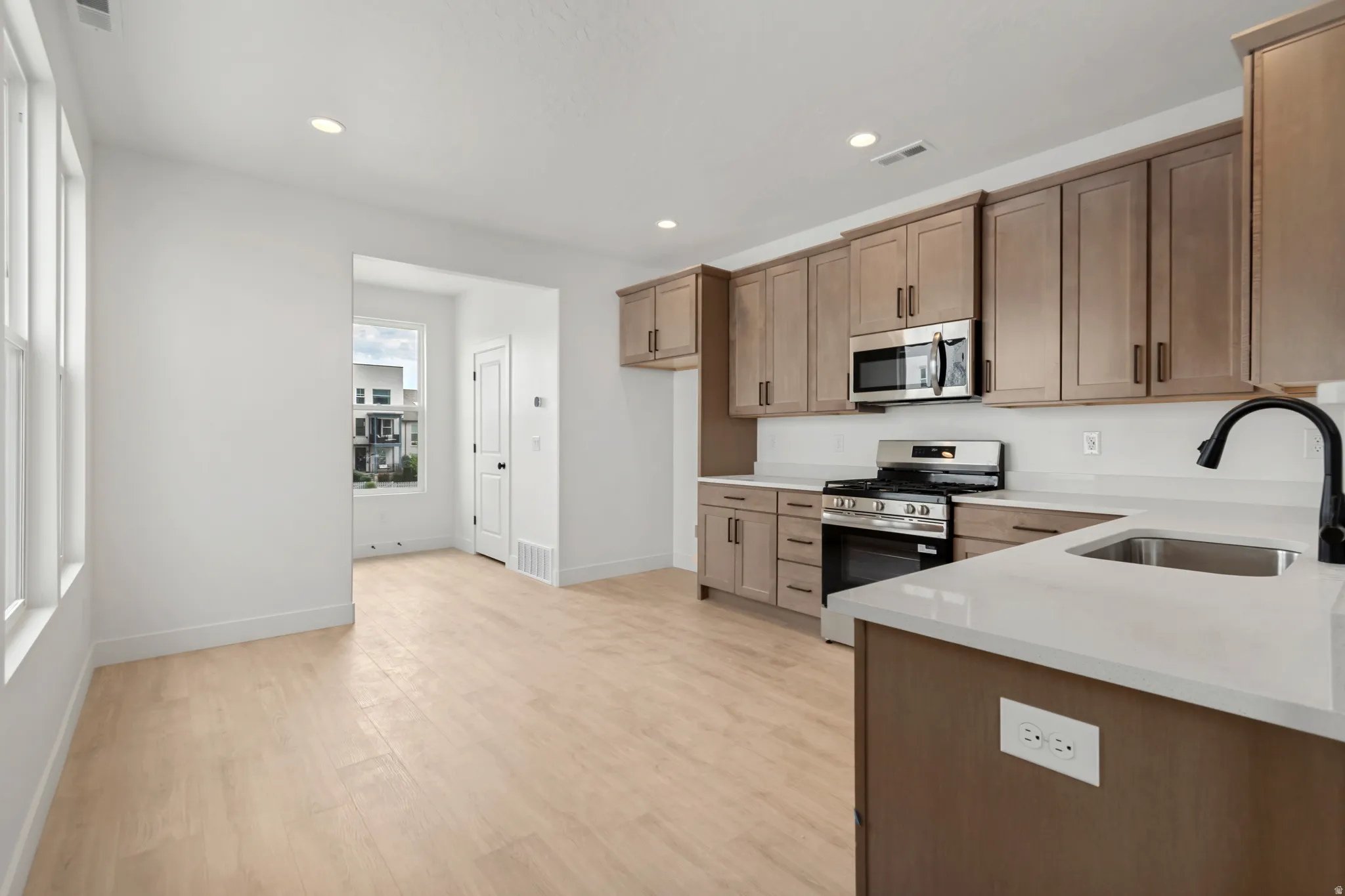 Kitchen featuring light wood-finish flooring, stainless steel appliances, solid surface countertops, and recessed lighting