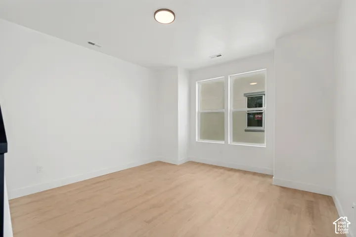 Recessed lighting, light wood-finish flooring, white walls, two vertical windows