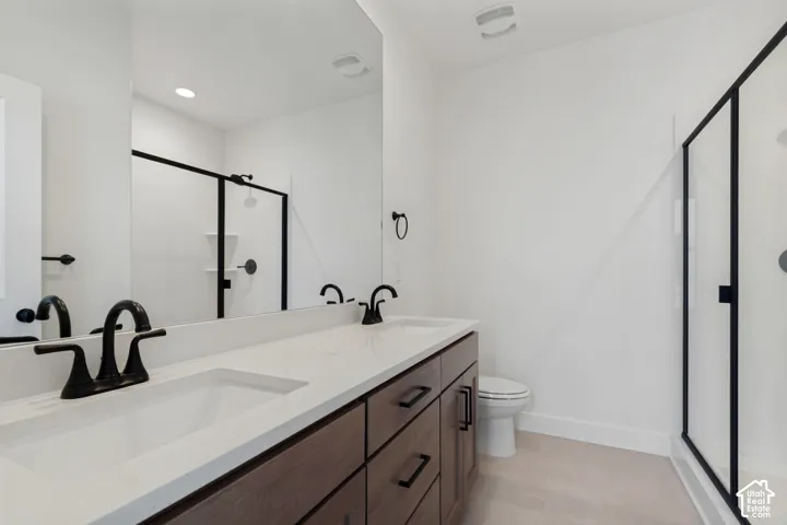 Dual vanity with integrated sinks, quartz countertop, dark wood-finish cabinetry with matte black hardware, and a glass-enclosed shower with matte black framing