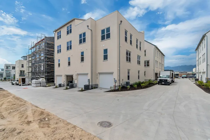 Multi-story stucco exterior with multiple garage bays, contemporary windows, and structured landscaping
