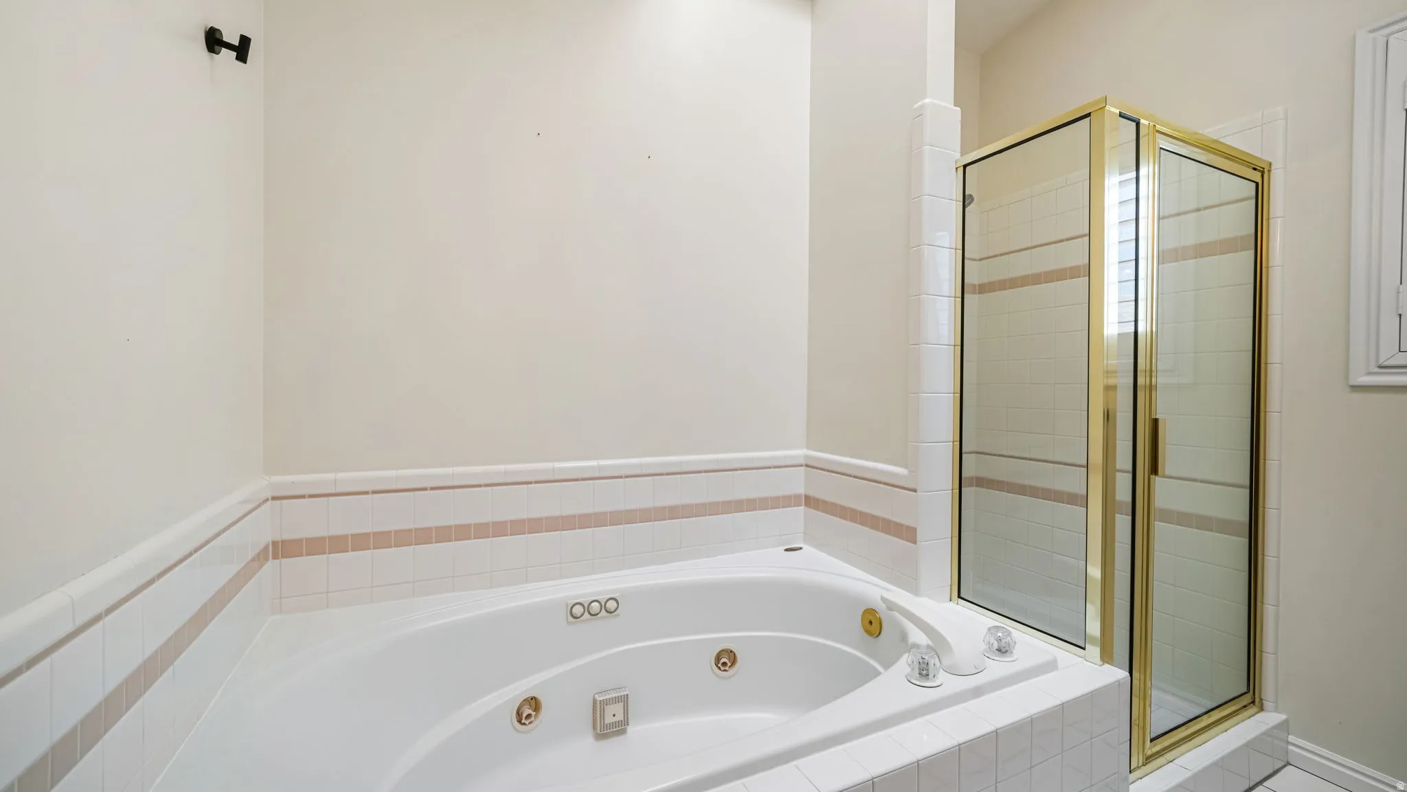 Jetted soaking tub with a tiled surround featuring accent banding