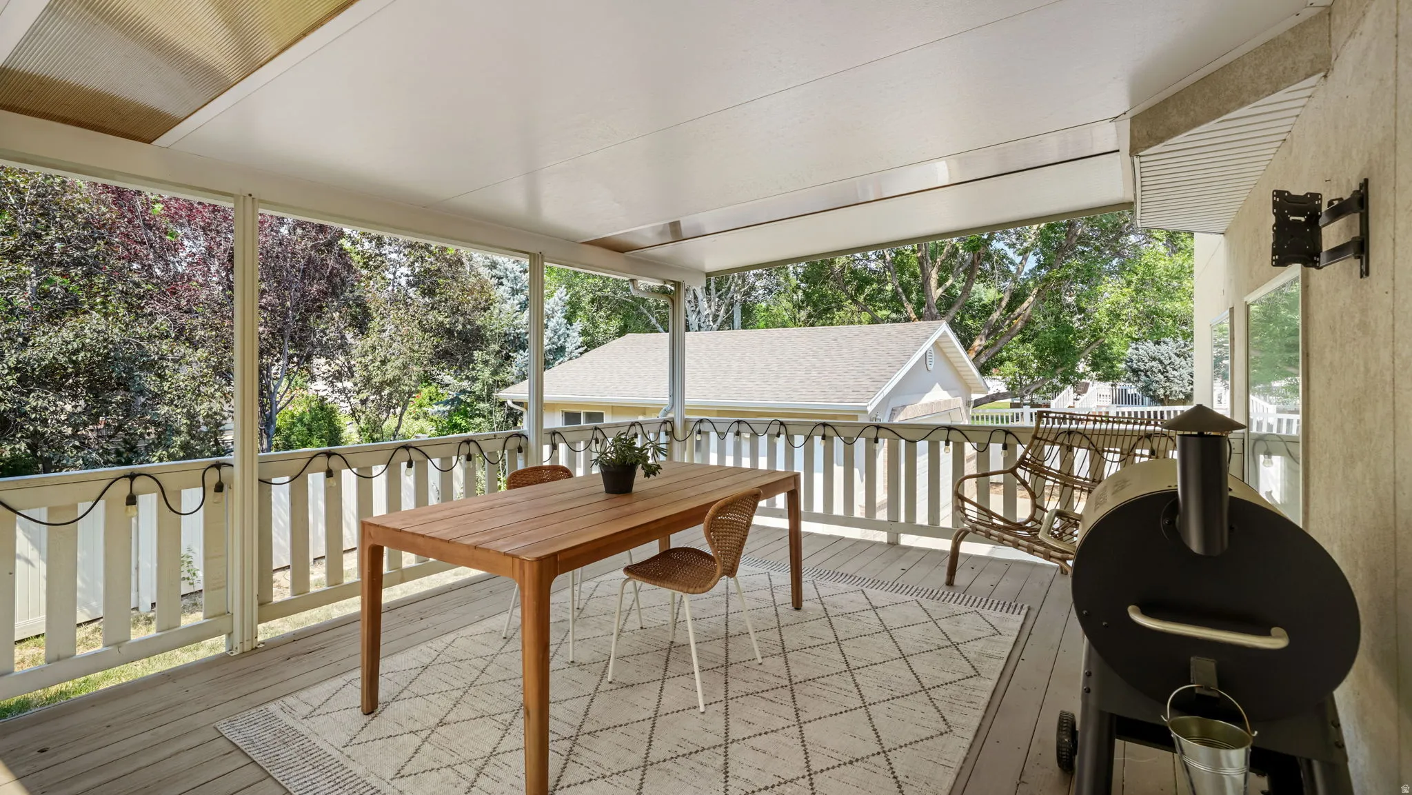 Expansive covered deck featuring wood-finish flooring, a white railing, and a slatted ceiling