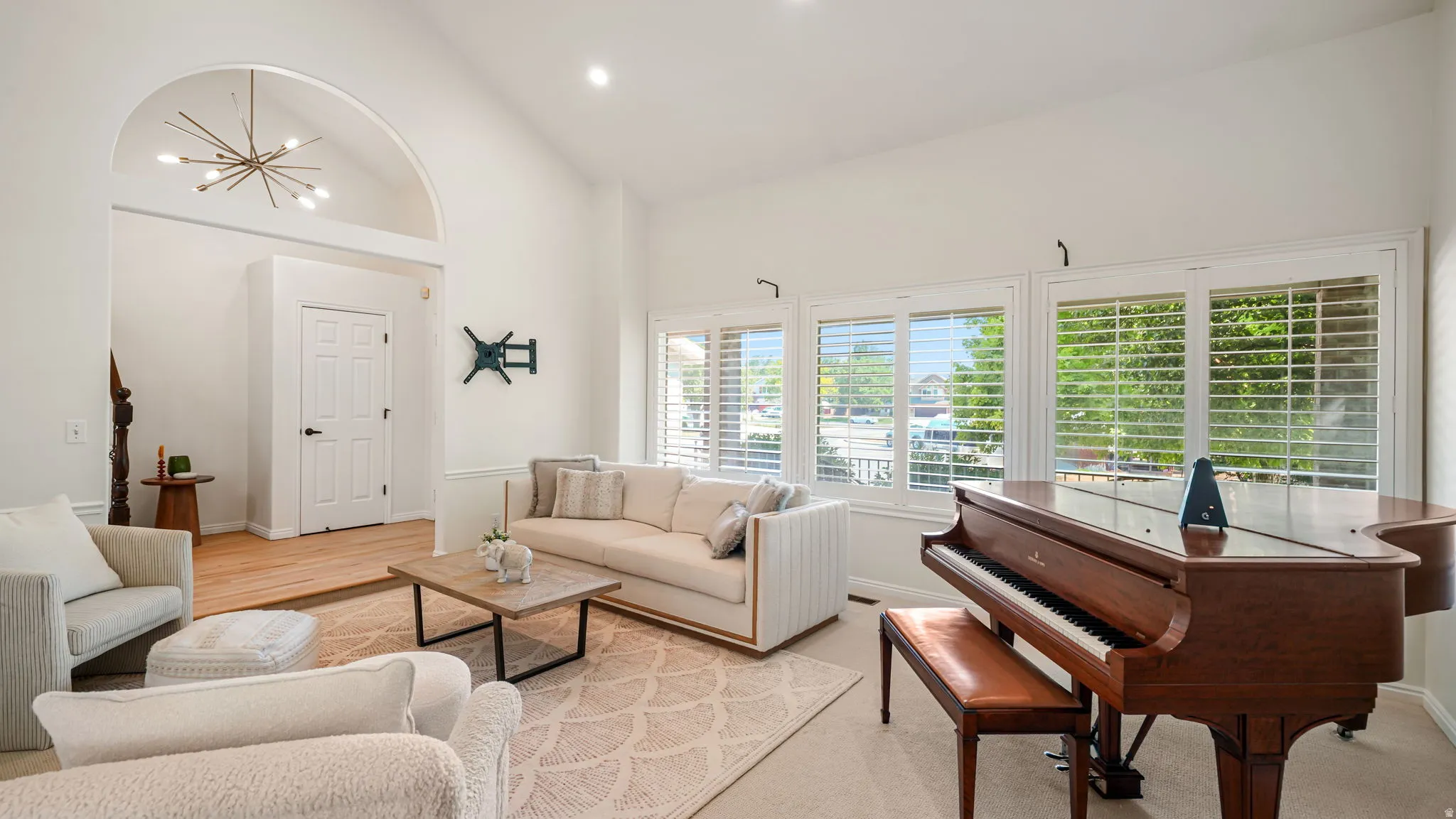 Spacious living area featuring high vaulted ceilings, multiple windows with plantation shutters, recessed lighting, and an arched entryway