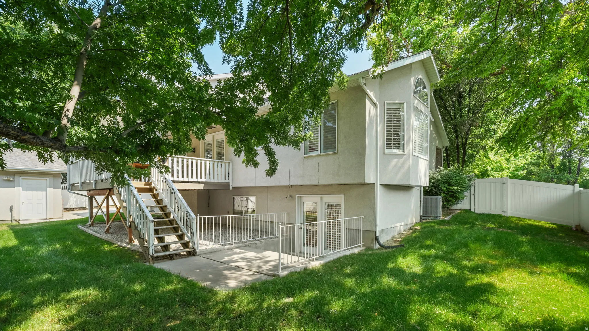 Rear exterior with a concrete patio, white railing, and dual-pane glass doors