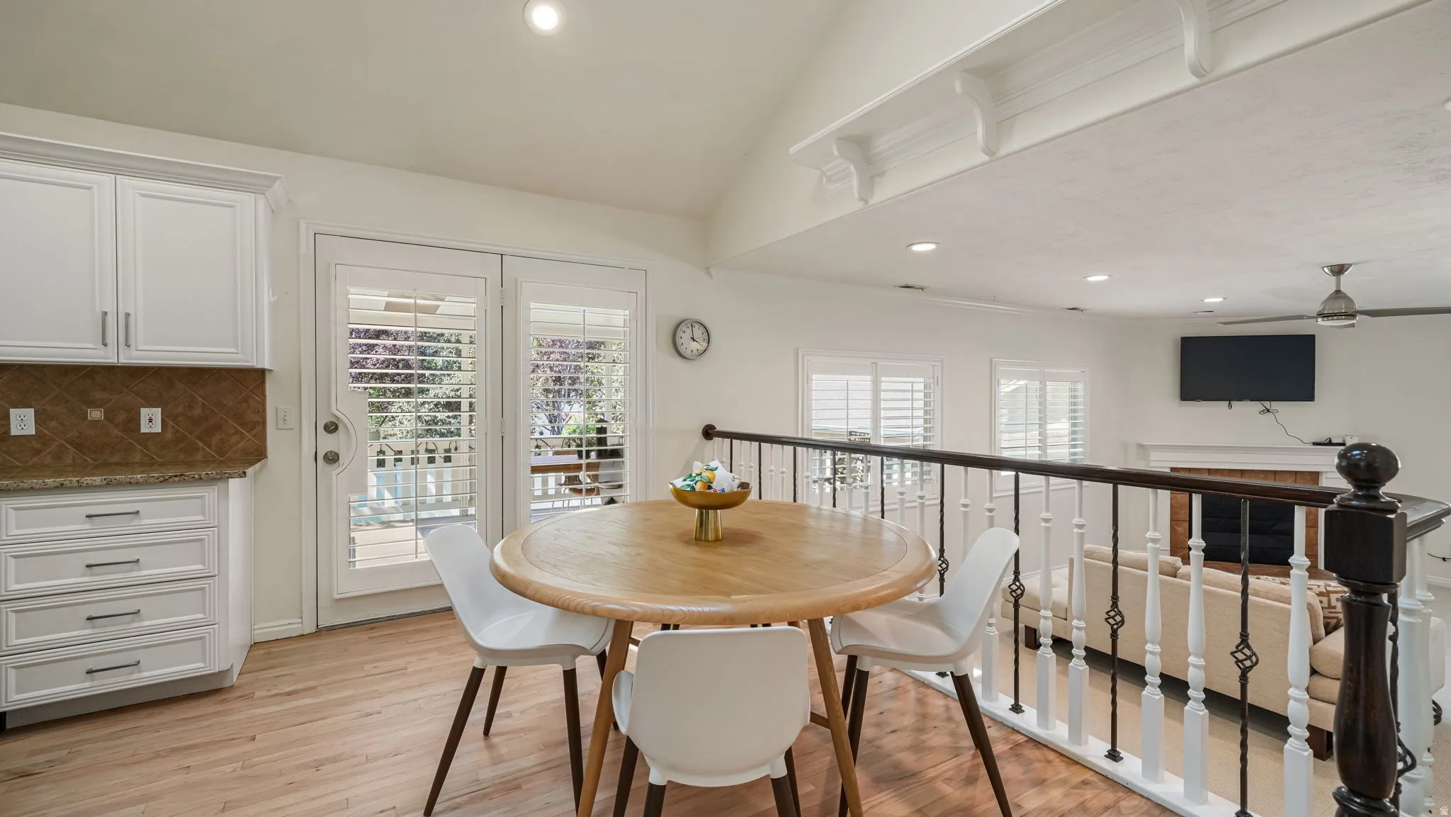 Kitchenette with wood-finish flooring, white cabinetry, and a patterned tile backsplash
