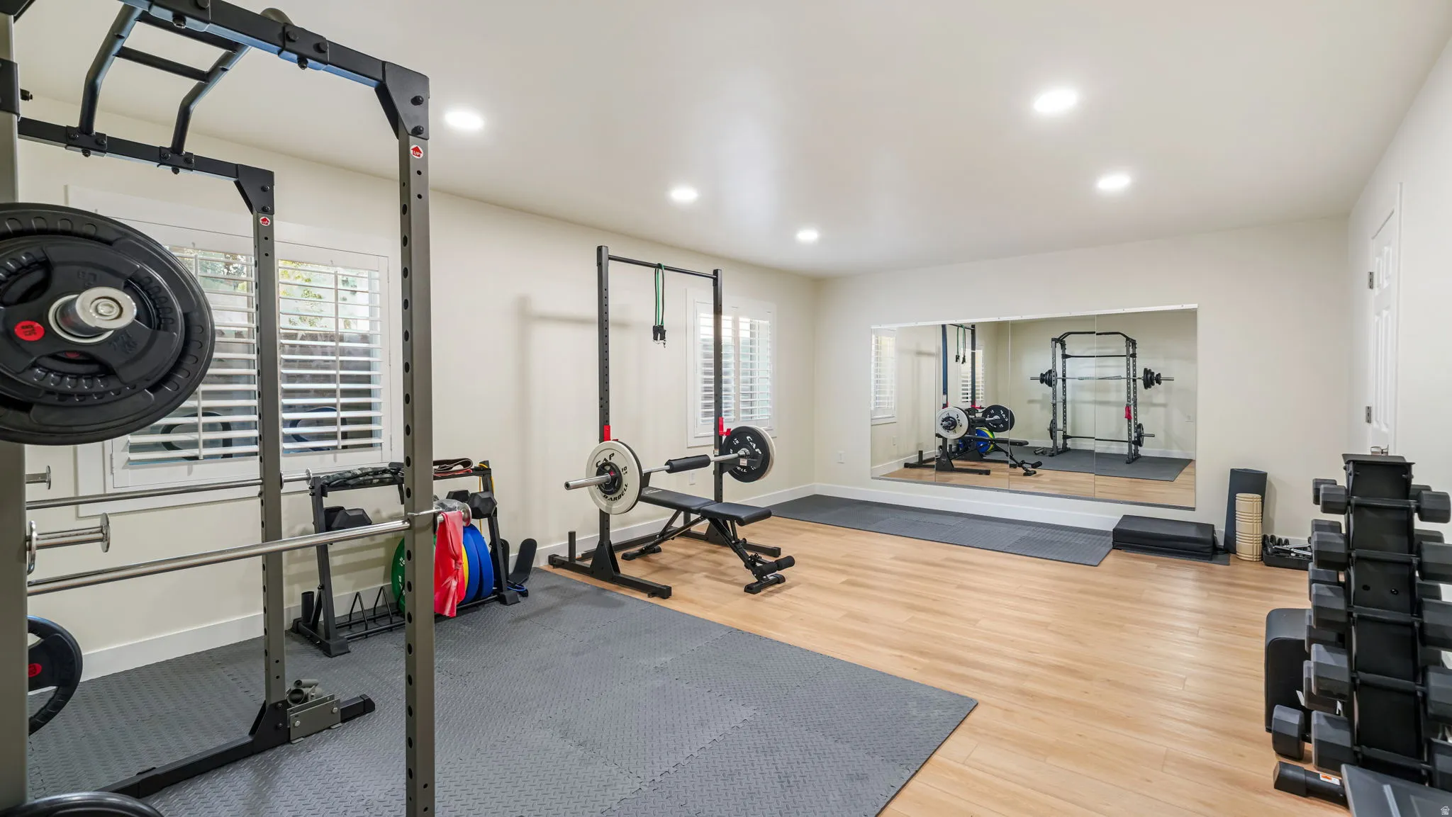 Dedicated fitness space featuring wood-finish flooring, recessed lighting, and a large wall-mounted mirror