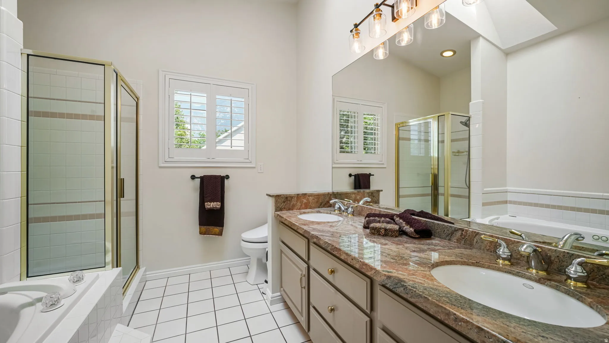Double vanity with stone countertop, dual sinks, and gold-tone fixtures