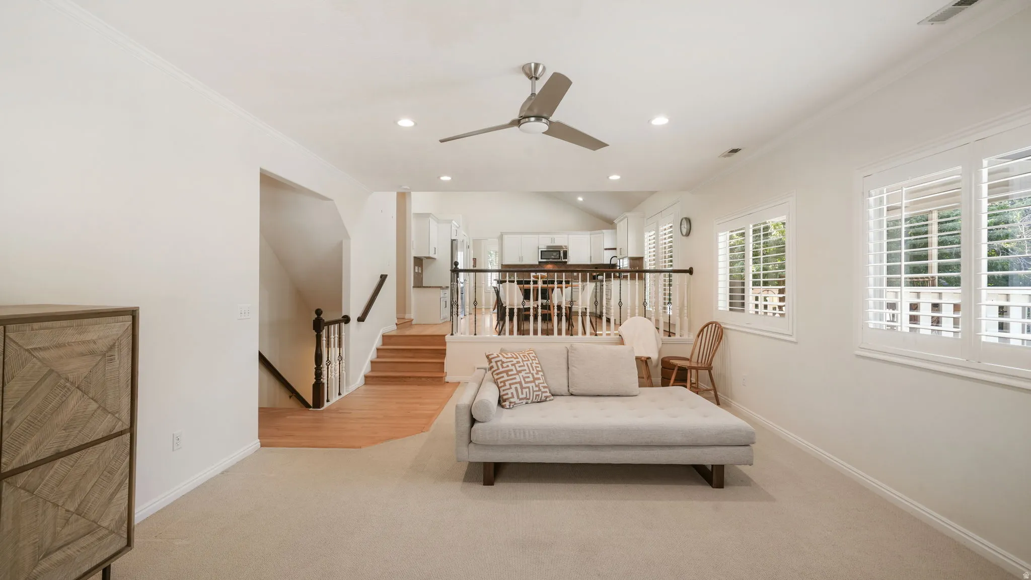 Spacious living area featuring neutral carpeting, a ceiling fan with integrated lighting, and recessed lighting