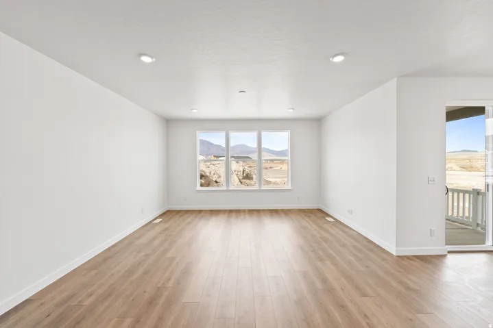 Spacious room featuring light wood-finish flooring and recessed ceiling lighting
