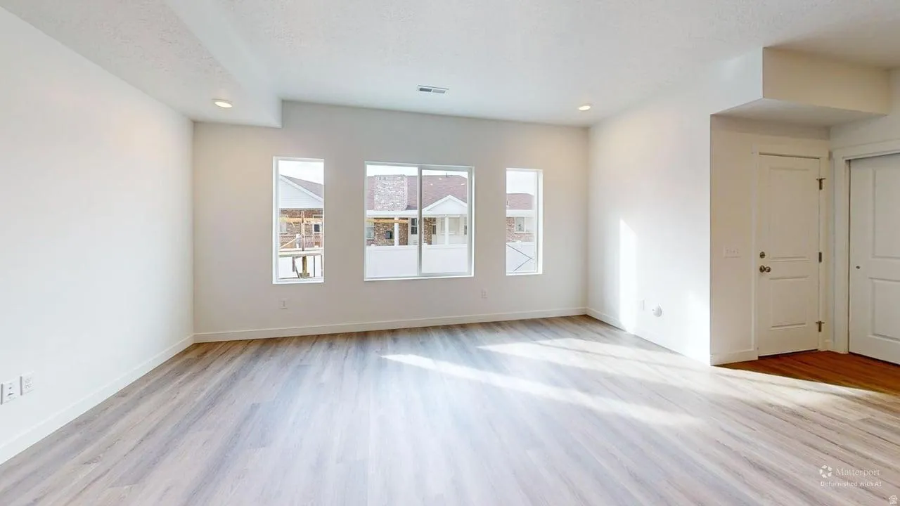 Spacious room with light wood-finish flooring, recessed lighting, and multiple windows