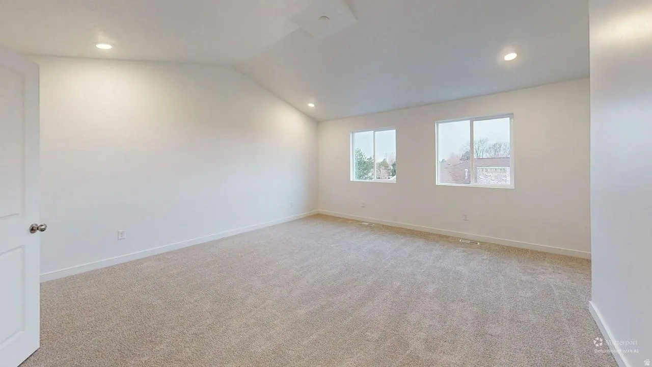 Spacious room featuring neutral carpet flooring, recessed lighting, and two windows providing exterior light