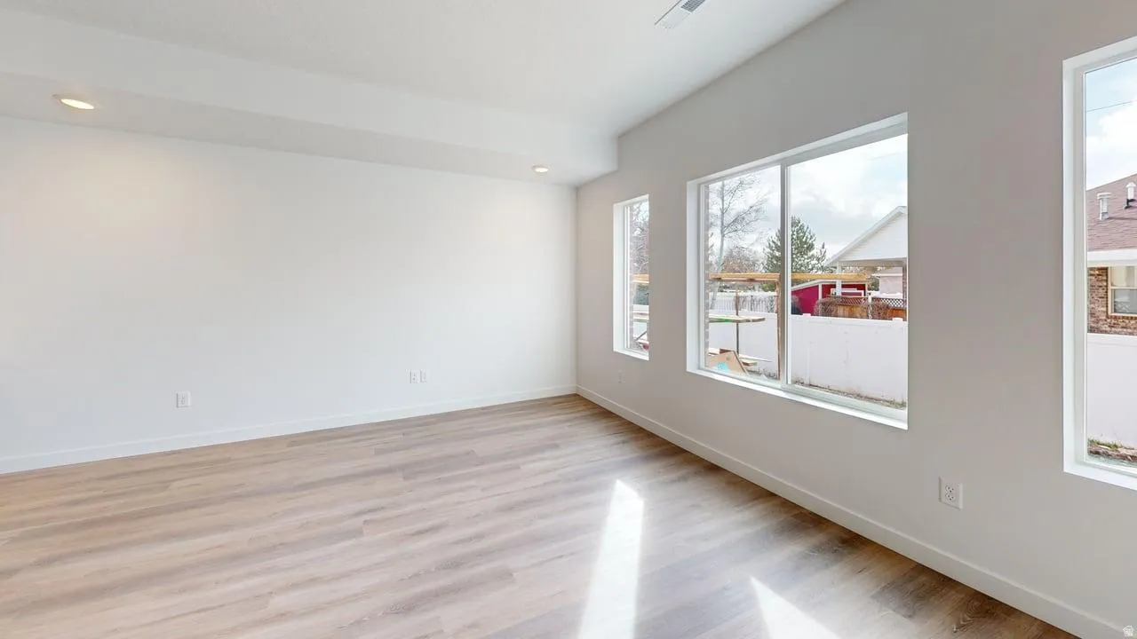 Open concept room featuring wood-finish flooring, recessed lighting, and multiple large windows with white trim
