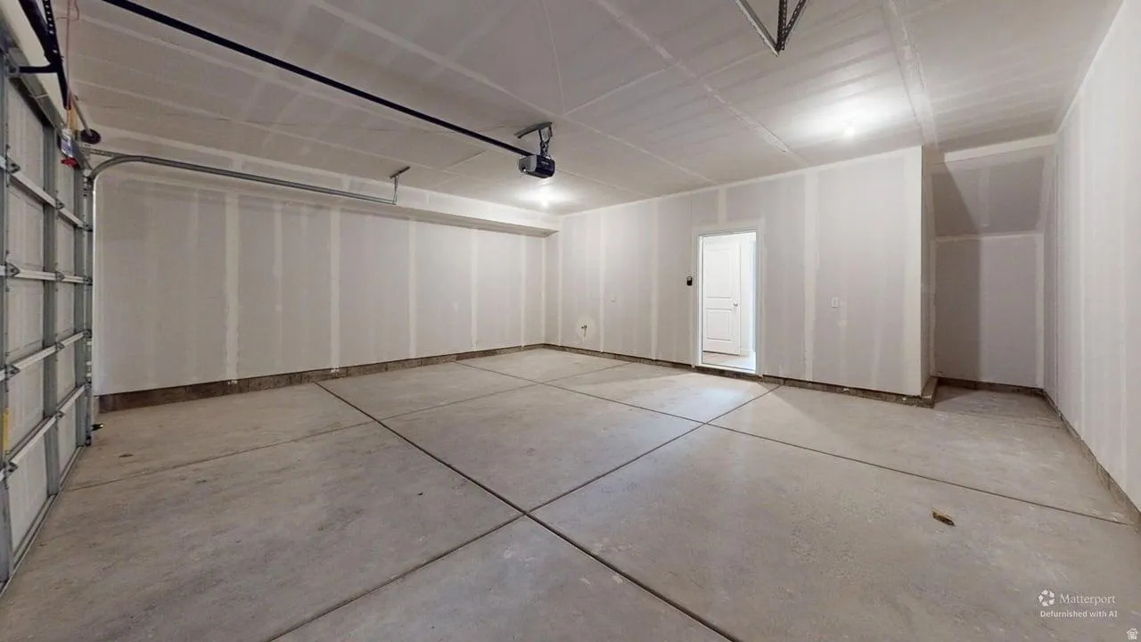Spacious garage with exposed drywall, concrete flooring, and an overhead garage door