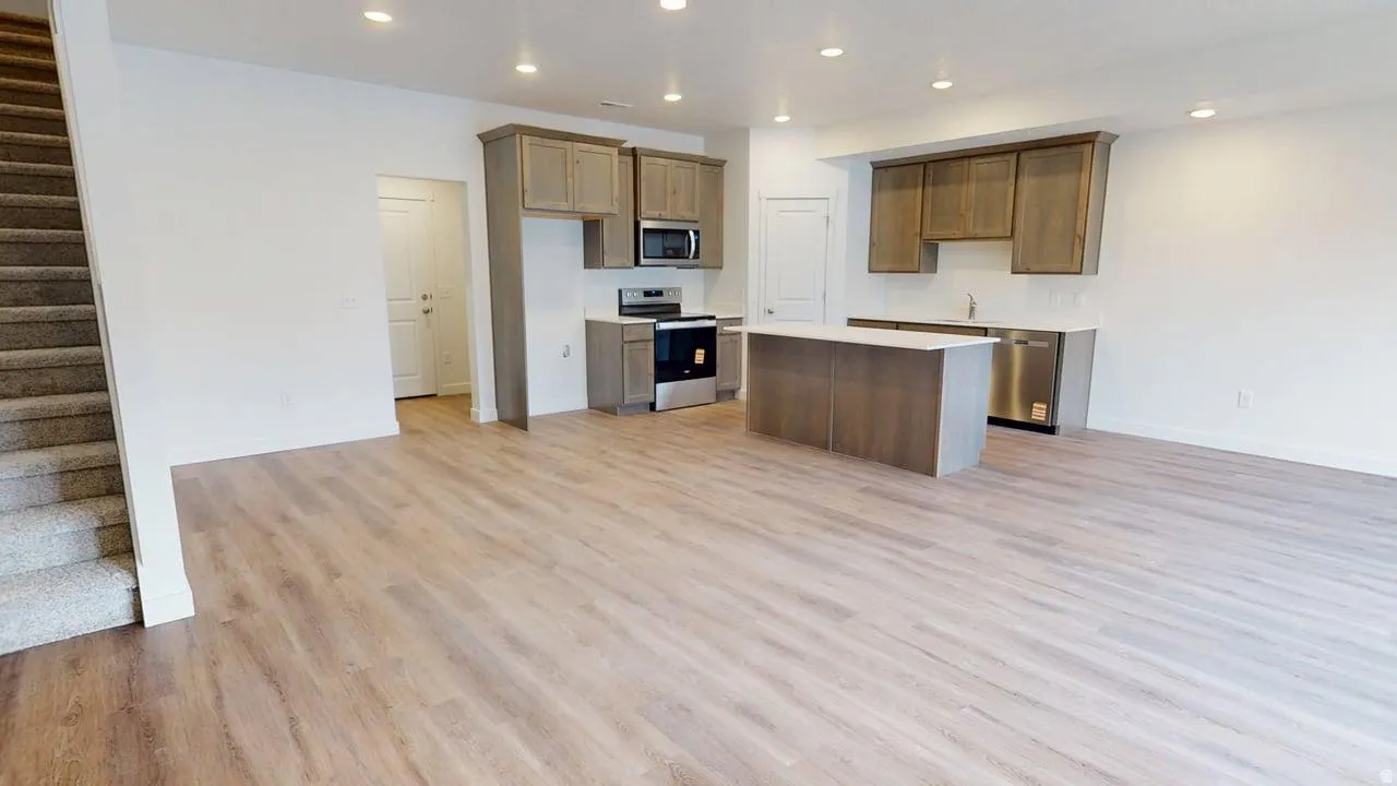 Open-concept living space featuring wood-finish flooring, recessed lighting, and a neutral color palette