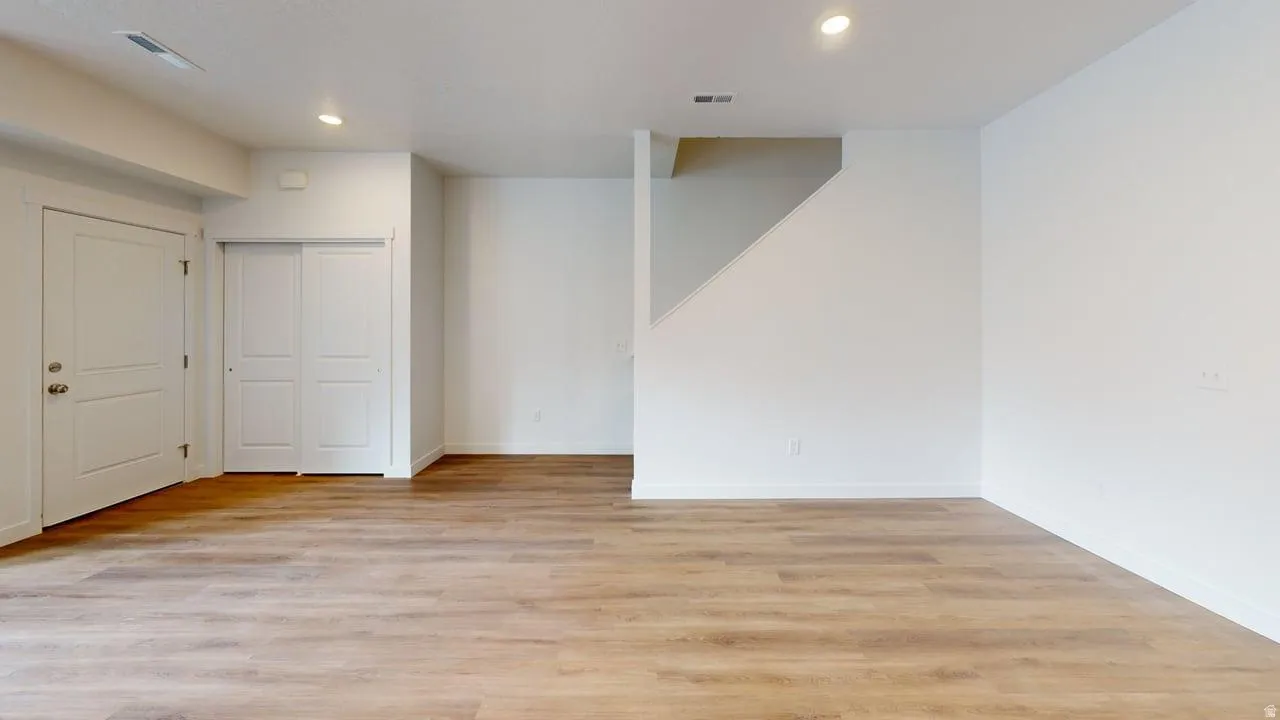 Spacious room featuring wood-finish flooring, recessed lighting, and bright white walls