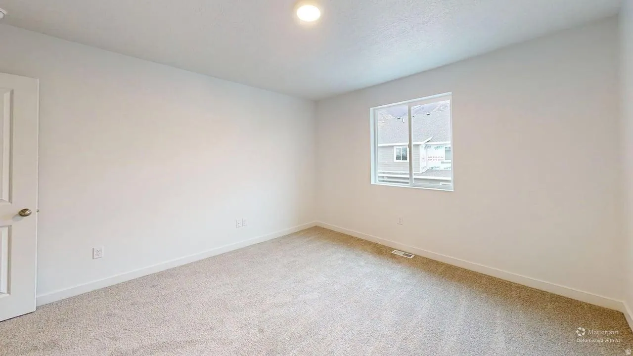Carpeted room featuring a white interior door with a brass-finish knob, white baseboards, and a single window with white trim