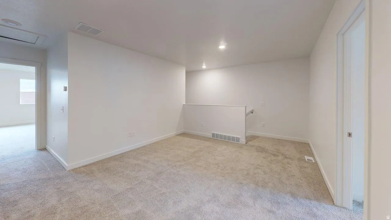 Spacious carpeted landing featuring recessed lighting, white baseboards, and a half-wall partition