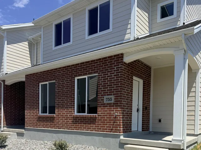 Two-story brick and siding construction featuring a covered front entry with white columns and a concrete walkway