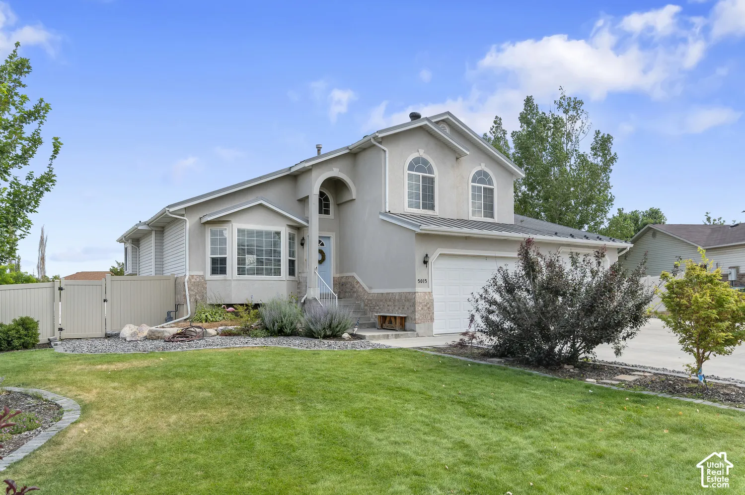 Two-story residence featuring a stucco exterior with stone accents, an arched entry, and a two-car garage