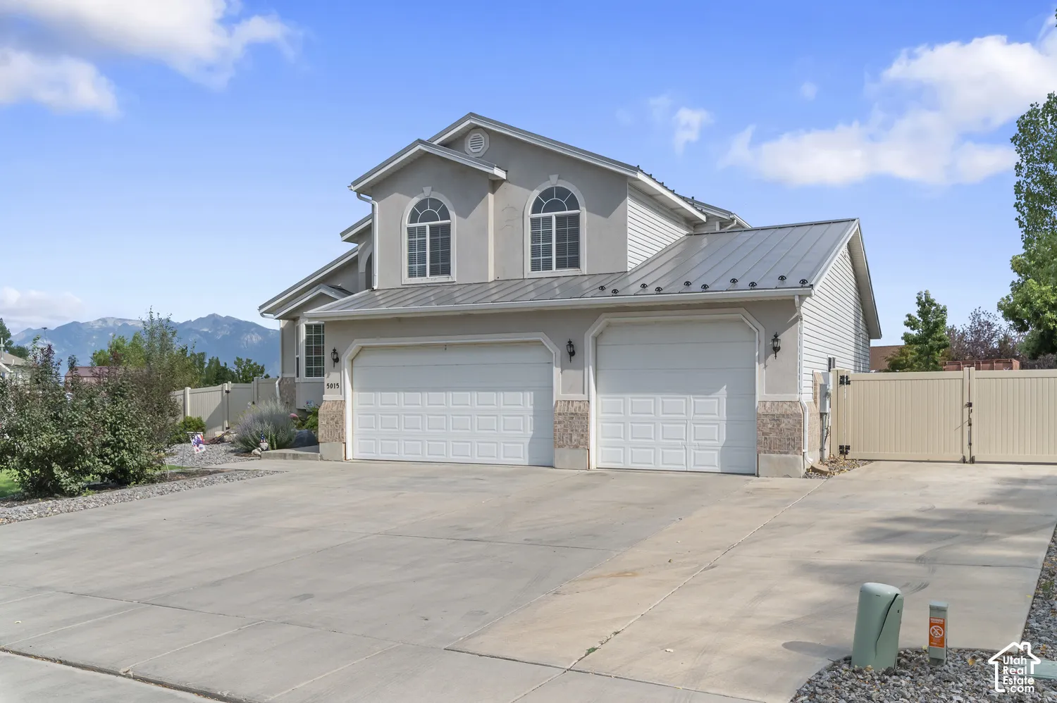 Stucco exterior featuring a metal roof and two-car garage