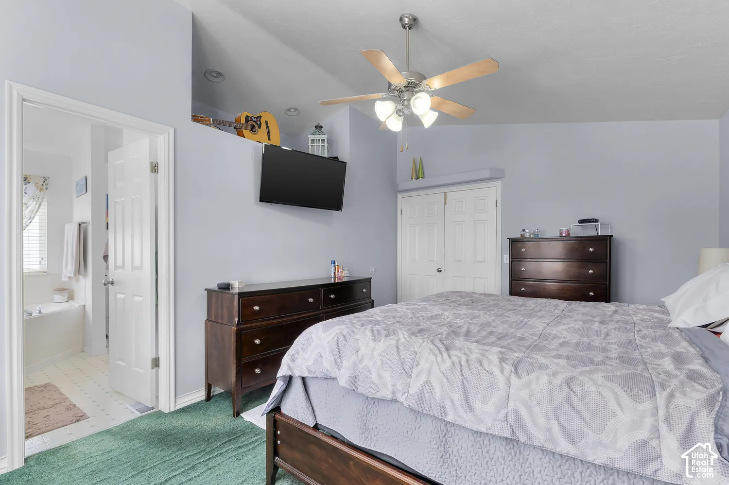 Interior room featuring a vaulted ceiling with a ceiling fan, a wall-mounted television, and a built-in shelf
