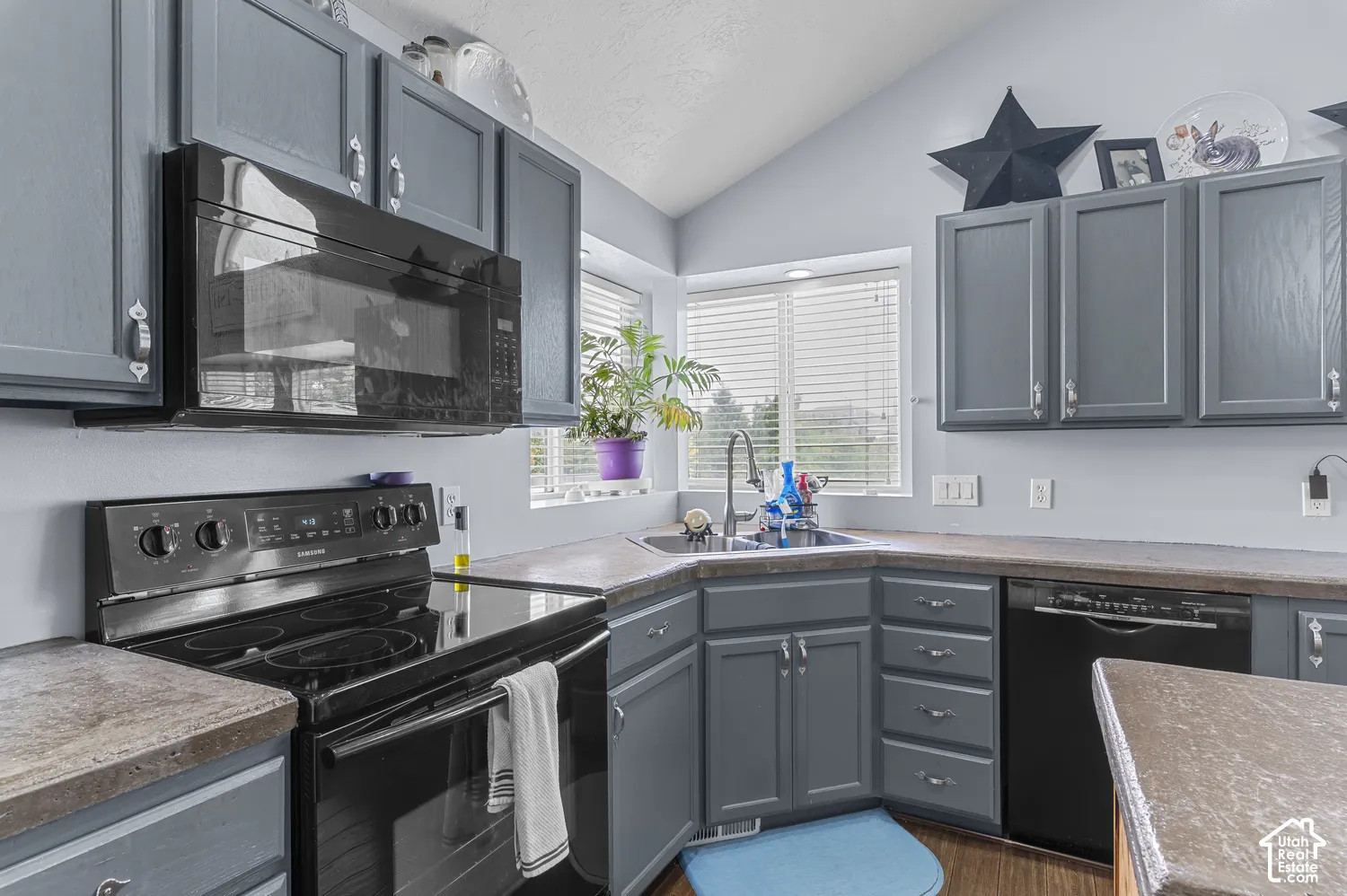 Kitchen featuring slate-toned cabinetry, laminate countertops, a black electric range, and an over-the-range microwave