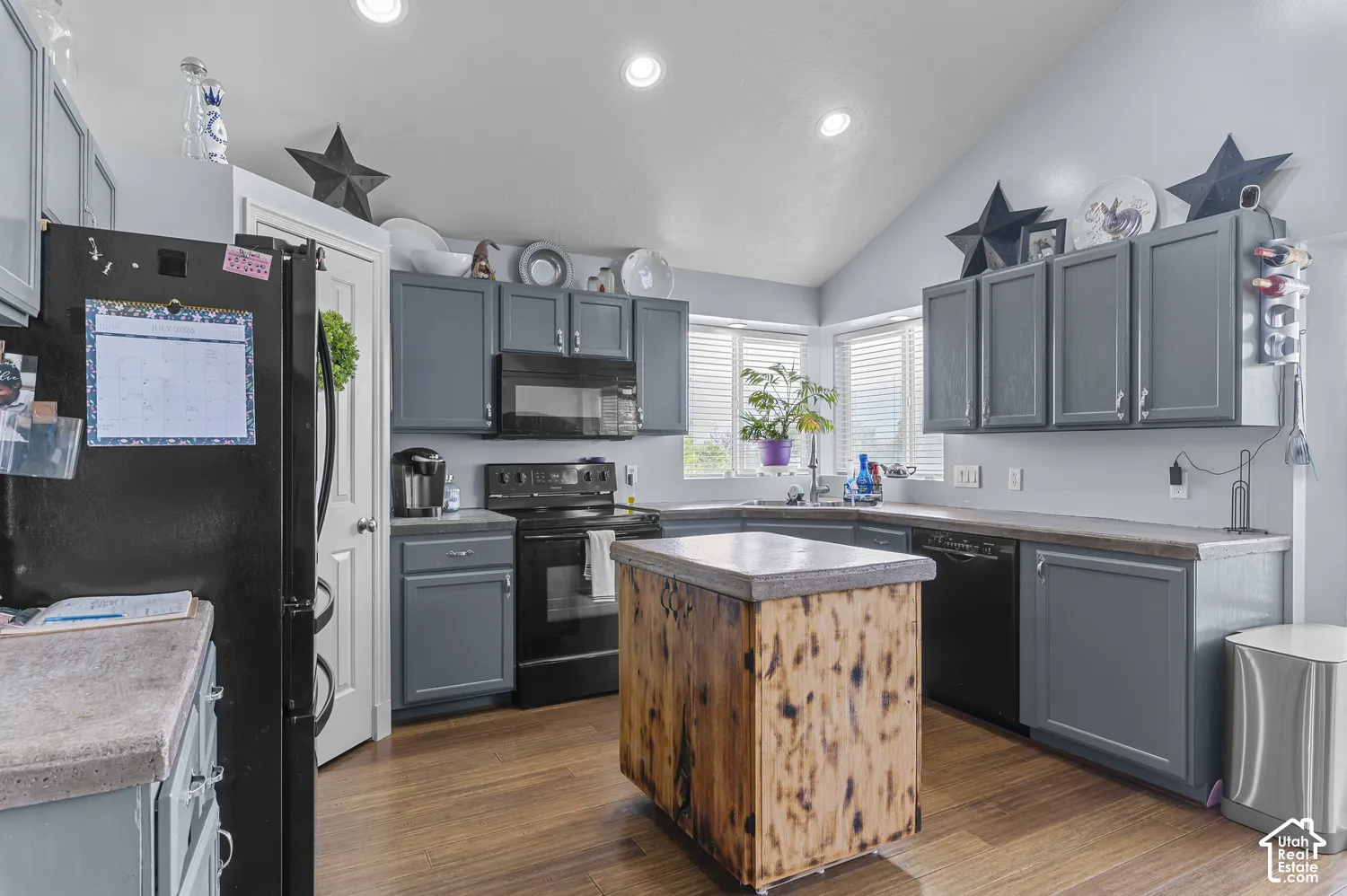 Kitchen featuring wood-finish flooring, vaulted ceilings, recessed lighting, and a bay window