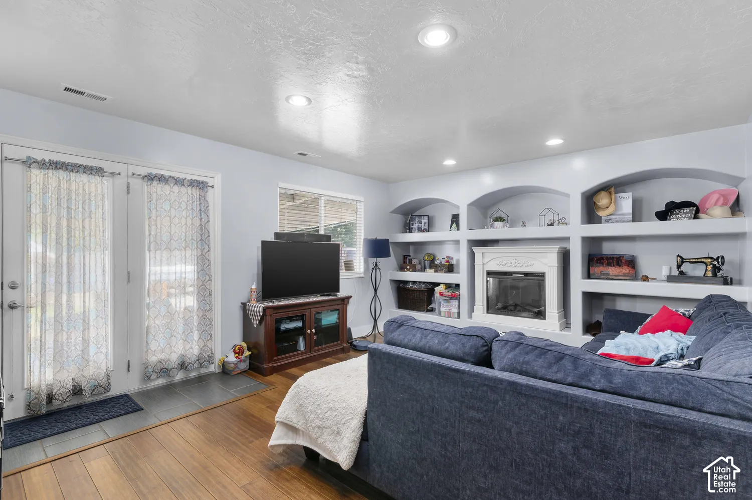 Living area with wood-finish flooring, recessed lighting, and a white fireplace mantel