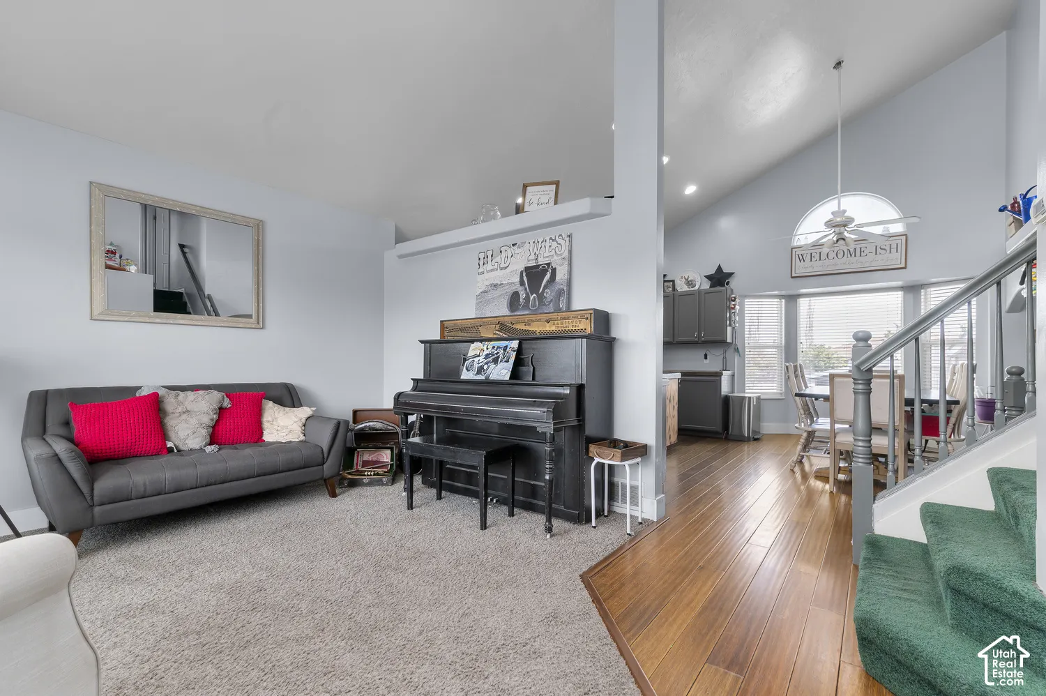 Open-concept living space featuring vaulted ceilings, wood-finish flooring, and an arched window
