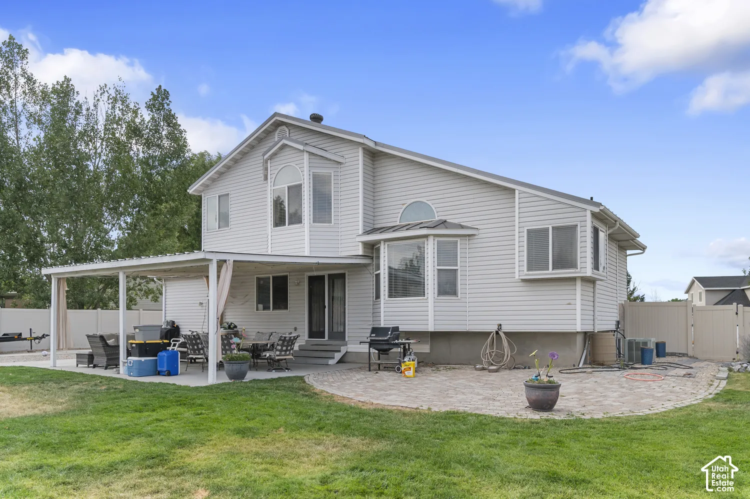Rear exterior featuring a covered patio, extensive paver patio, bay windows, and siding facade