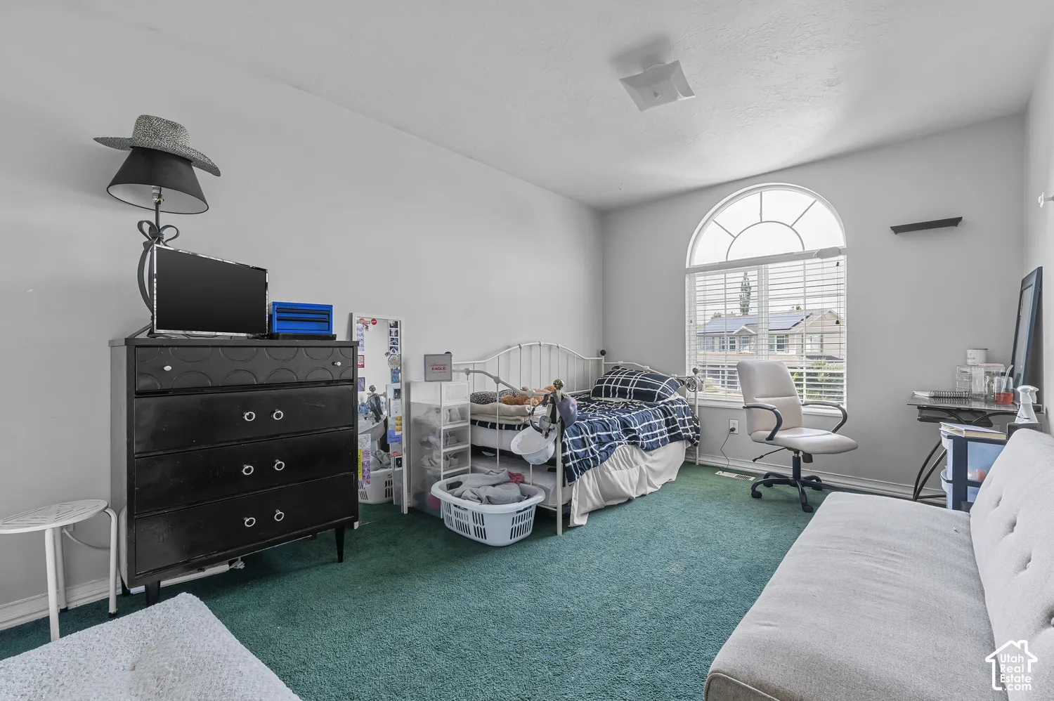 Room featuring a large arched window with blinds, light gray walls, and green carpeting