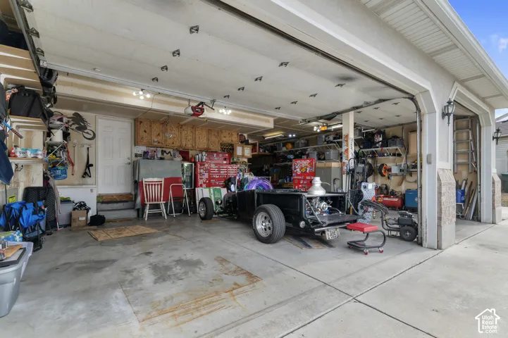 Spacious multi-car garage featuring two overhead doors, overhead storage, built-in cabinetry, and a concrete floor