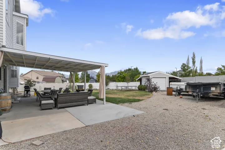 Expansive rear yard featuring a covered patio, concrete patio surface, and a gravel parking area