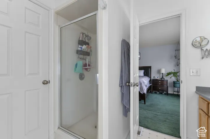 Glass-enclosed shower with a white surround and chrome fixtures
