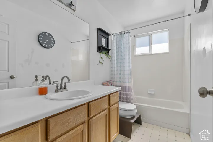 Bathroom featuring a wood-finish vanity with a white countertop and an integrated sink